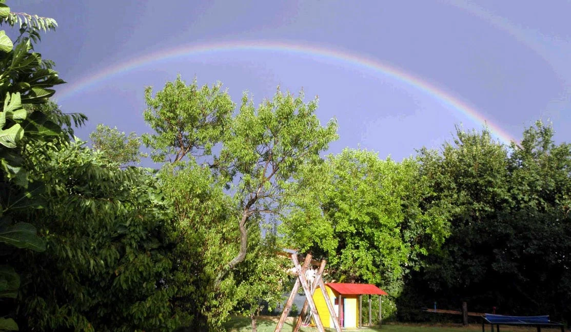 Un arcobaleno sopra il giardino dell’agriturismo con giochi all’aperto